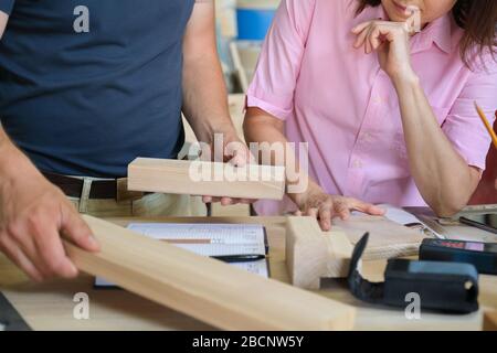 Naharbeiten in der Tischlermöbelwerkstatt, Hände von Arbeitern mit Holzproben Stockfoto