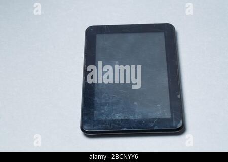 Schwarz verkratztes Tablett mit einer Schutzfolie auf grauem Hintergrund. Schützen Sie den Bildschirm Ihres Geräts Stockfoto