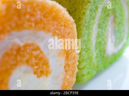 Texturdetails auf der Oberfläche von cremefarbenem und orangefarbenem Rollkuchen Stockfoto