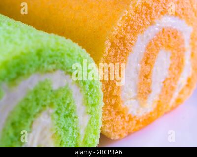 Texturdetails auf der Oberfläche von cremefarbenem und orangefarbenem Rollkuchen Stockfoto