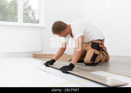 Außenarbeiter mit Laminatboden. Längsgelenk - die Reihenfolge der technologischen Verfahren zum Verlegen und Einbau von Bodenbelägen - Laminat - professionelle Arbeit Stockfoto