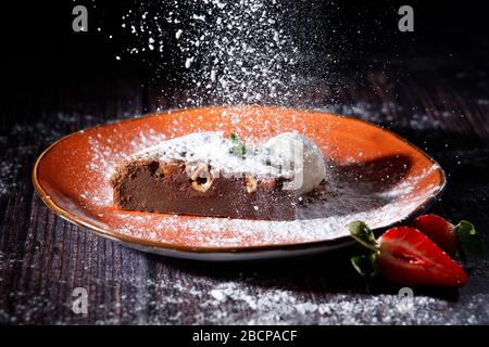 Brownies bestreut mit Mandeln und Minze, die auf einer orangefarbenen Platte gestapelt sind.Brownies sind eine Art Schokoladenkuchen. Stockfoto