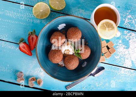 Tiramisu aromatisierte Schokoladentrüffel Pralinen süße Mini-Imbiss-Kugeln auf einem blauen Plattenhintergrund Stockfoto