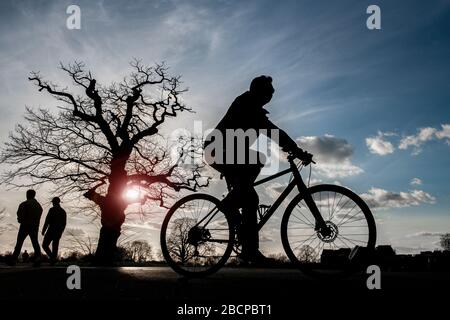 Ein Radfahrer hält sich im März 2020 bei einem dramatischen Sonnenuntergang fit (unter den Einschränkungen für Corona Virus Covid 19) Stockfoto