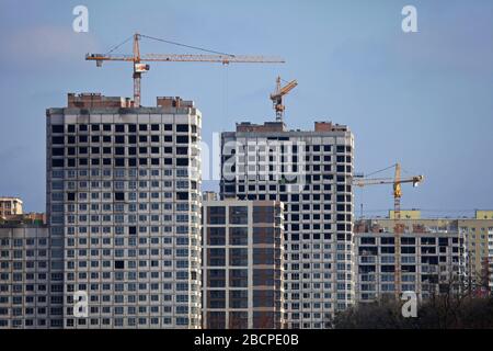 Kiew, Ukraine - 17. Februar 2019: Hochhauskrane und eine Reihe von Gebäuden im Bau auf dem blauen Himmel Hintergrund Stockfoto