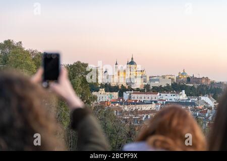 Unerkennbare Touristen machen Fotos und genießen die Aussicht auf die Almudena und den Königspalast. Madrid, Spanien. Reisekonzept und Technologie. Stockfoto