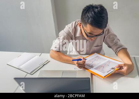 Asiatischer Büroangestellter liest Finanzberichte im Büro Stockfoto