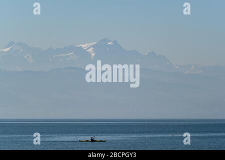 Langenargen, Deutschland. April 2020. Ein Kajaker paddelt über den Bodensee, im Hintergrund ist der Säntis in der Schweiz zu sehen. Auf dem Bodenseeufer gab es nur wenige Boote. Kredit: Felix Kästle / dpa / Alamy Live News Stockfoto