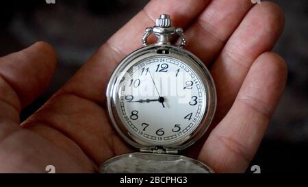 Alte, antike Taschenuhr, die die Zeit zeigt, die in der Hand gehalten wird. Nahaufnahme Stockfoto