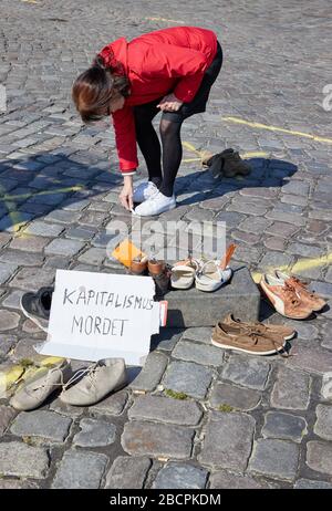 Hamburg, Deutschland. April 2020. Eine Frau zieht die Umrisse ihres Schuhs mit Kreide auf den Pflaster am St. Pauli Fischmarkt. Im Vordergrund steht ein Karton mit der Aufschrift: "Kapitalismus-Morde" und Paar Schuhe ausgestellt. Ein bundesweiter Aktionstag von "Seebrücke Hamburg" und "Freitags für die Zukunft" unter dem Motto "#LeaveNoOneBehyd" fordert sowohl die Räumung der Lager als auch die Eröffnung der leerstehenden Hotels zur Unterbringung von Obdachlosen und Flüchtlingen. Credit: Dpa / Alamy Live News Stockfoto