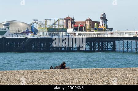 Brighton UK 5. April 2020 - EIN Mann liegt am Brighton Strand an einem warmen sonnigen Tag mit Temperaturen, die während der Coronavirus COVID-19-Pandemie-Krise voraussichtlich zwanzig Grad in London erreichen werden. Gesundheitsminister Matt Hancock hat heute gesagt, dass sie die Regeln für die Ausübung möglicherweise überarbeiten müssen, da zu viele Menschen die Richtlinien ignorieren. Kredit: Simon Dack / Alamy Live News Stockfoto