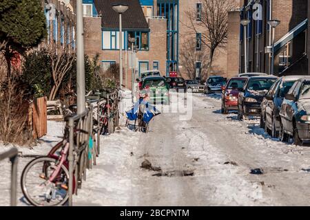 Winterstraßenlandschaft mit Sozialwohnungen, Fahrrädern und Autos in Amsterdam, Niederlande Stockfoto