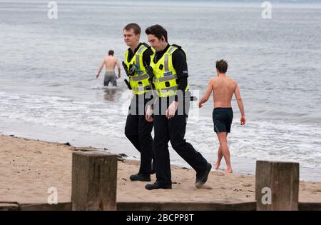 Portobello, Edinburgh, Schottland, Großbritannien. April 2020. Am zweiten Sonntag des Coronavirus Sperrens in Großbritannien nimmt die Öffentlichkeit ihre tägliche Übung nicht ab. Abgebildet. Die Polizei spricht mit dem Mann in Badehosen am Strand von Portobello. Nach der Diskussion durfte der Mann weiter schwimmen. Iain Masterton/Alamy Live News Stockfoto