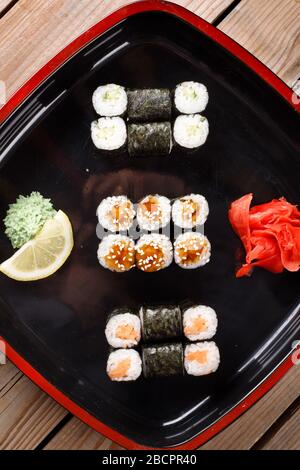 Gebackene Sushi-Brötchen mit Wasabi und Ingwer auf schwarzem Hintergrund. Japanische orientalische Küche Stockfoto