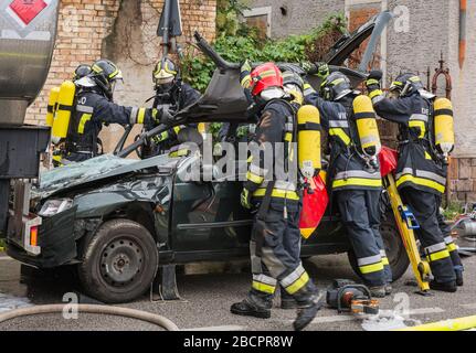 Feuerwehrleute retten eingeklemmten Fahrer während einer Unfallsimulation mit Autos, Zug und Lastwagen. Feuerwehrleute mit Atemschutzgerät und Hyd Stockfoto