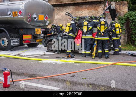 Feuerwehrleute retten eingeklemmten Fahrer während einer Unfallsimulation mit Autos, Zug und Lastwagen. Feuerwehrleute mit Atemschutzgerät und Hyd Stockfoto