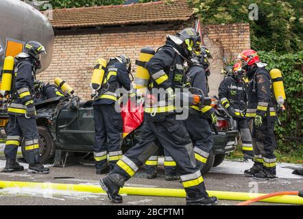 Feuerwehrleute retten eingeklemmten Fahrer während einer Unfallsimulation mit Autos, Zug und Lastwagen. Feuerwehrleute mit Atemschutzgerät und Hyd Stockfoto