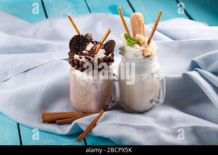 Karamell und Schokolade verwöhnen extreme Milchshakes mit Schokoladenkuchen, Plätzchen, Marshmallows und Süßigkeiten. Verrückte Tendenz zum Verwackeln von Lebensmitteln. Stockfoto