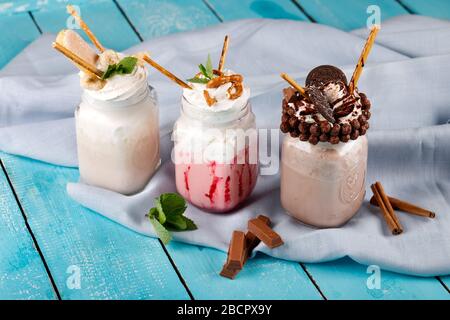 Karamell und Schokolade verwöhnen extreme Milchshakes mit Schokoladenkuchen, Plätzchen, Marshmallows und Süßigkeiten. Verrückte Tendenz zum Verwackeln von Lebensmitteln. Stockfoto