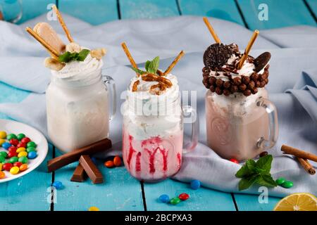 Karamell und Schokolade verwöhnen extreme Milchshakes mit Schokoladenkuchen, Plätzchen, Marshmallows und Süßigkeiten. Verrückte Tendenz zum Verwackeln von Lebensmitteln. Stockfoto