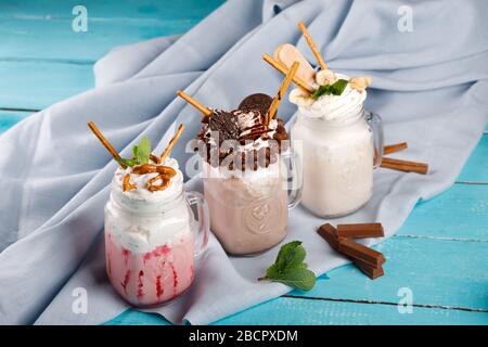 Karamell und Schokolade verwöhnen extreme Milchshakes mit Schokoladenkuchen, Plätzchen, Marshmallows und Süßigkeiten. Verrückte Tendenz zum Verwackeln von Lebensmitteln. Stockfoto