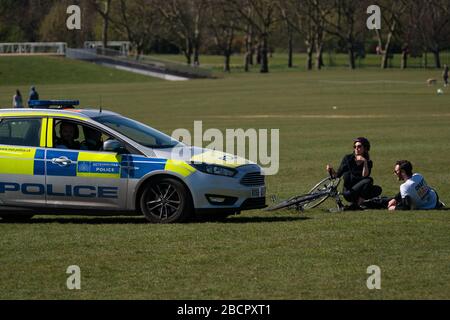 Die Polizei geht auf Sonnenbäder im Regenten Park, London, um die Ausbreitung des Coronavirus einzudämmen, während Großbritannien weiterhin in Sperrungen ist. Stockfoto