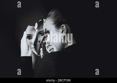 Schöne brünette Frau und kaputter Selbstbildspiegel auf Schwarz Stockfoto