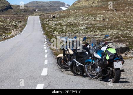 Drei Motorräder stehen am Straßenrand entlang der schmalen Asphaltstraße im Hochland Norwegens, Norwegian Scenic Route Aurlandsfjellet Stockfoto