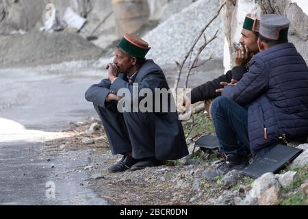 Passagiere genießen eine Rauchpause, während sie auf den nächsten Bus warten, da ihr Bus auf der Sangla Rakchham Road, Himachal Pradesh, Indien, zusammenbricht. Stockfoto