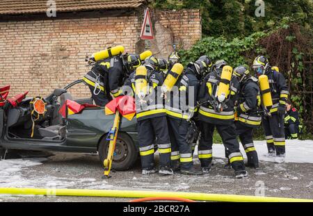 Feuerwehrleute retten eingeklemmten Fahrer während einer Unfallsimulation mit Autos, Zug und Lastwagen. Feuerwehrleute mit Atemschutzgerät und Hyd Stockfoto