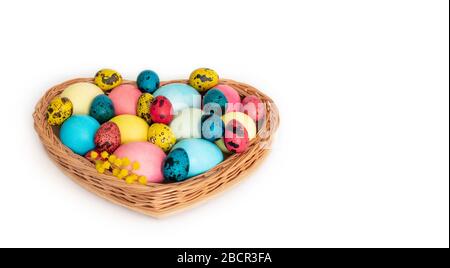 Osterzusammensetzung mit bunten Eiern in einem Korb auf weißem Hintergrund. Horizontale Ausrichtung. Kopierbereich. Seitenansicht. Stockfoto