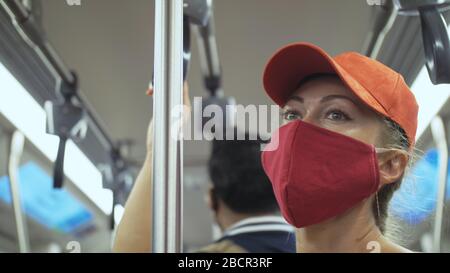 Frau fährt kaukasische Fahrt im überirdischen Zug airtrain mit Schutzmaske. Mädchen Tourist im airtrain mit Atemschutzmaske. Personenmaske. Stockfoto