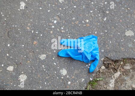 Blauer medizinischer Handschuh auf die Straße geworfen, auf den Boden. Stockfoto