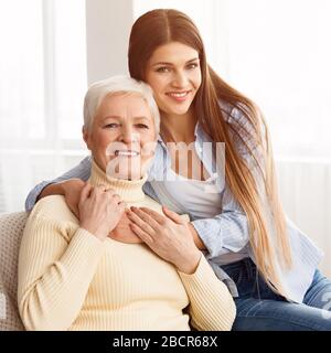 Zwei Generationen. Tochter, die ihre ältere Mutter umarmt Stockfoto