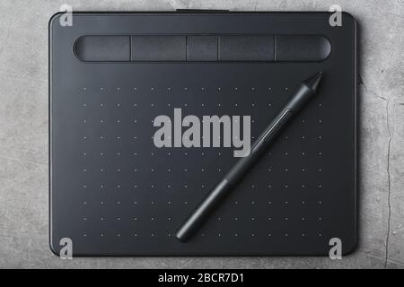 Grafiktablett mit einem Stift auf grauem Hintergrund, die Arbeit eines Designers, Künstlers und Fotografen. Die Ansicht von oben Stockfoto