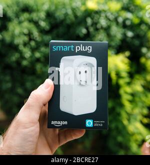 Paris, Frankreich - 1. August 2019: Männliche Hand mit neuem Amazon SMART-Stecker in Zusammenarbeit mit Alexa Personal Assistant - grüner Hintergrund Stockfoto