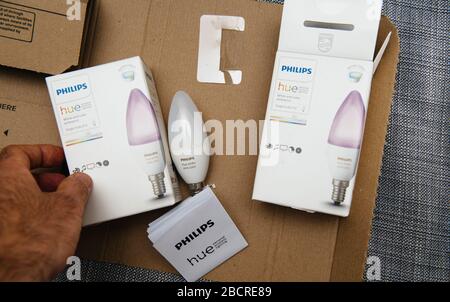 Paris, Frankreich - 7. August 2019: Männliche Hand der POV über dem Paket "Unboxing" von Amazon Prime mit zwei neuen, mit dem Internet verbundenen Philips Hue E14-Glühbirnen in Farbe und weißem Ambiente Stockfoto