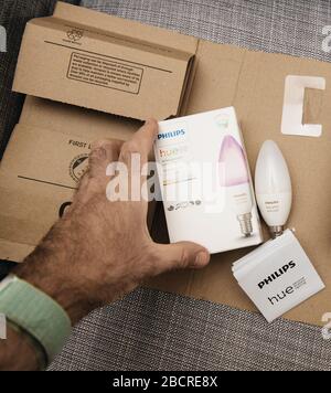 Paris, Frankreich - 7. August 2019: Blick von oben auf das männliche Hand-Unboxing-Paket von Amazon Prime mit zwei neuen, mit dem Internet verbundenen Philips Hue E14-Farblampen in weißer Atmosphäre Stockfoto