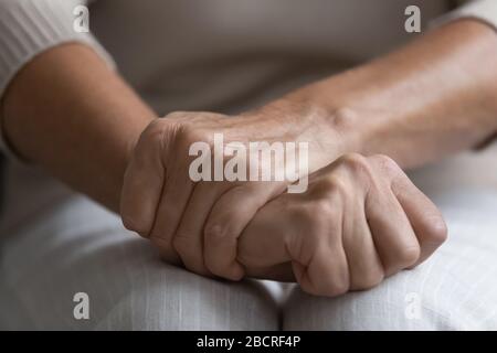 Seniorin mittleren Alters, die die zerknitterten Hände auf dem Schoß hält. Stockfoto