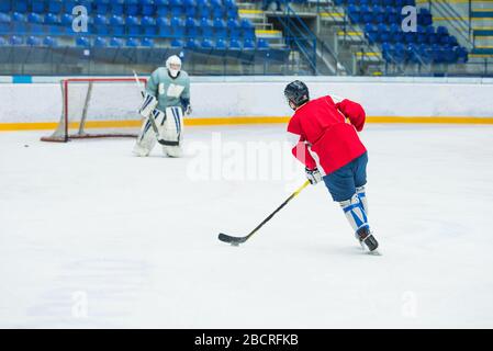 Eishockeyspieler auf dem Eis, professionelles Eishockeyspiel, Sportfoto, Torwart im Hintergrund Stockfoto