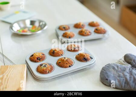 Der Konditorei gingen frisch gebackene Muffins in einer Backform auf dem Tisch aus dem Ofen. Stockfoto