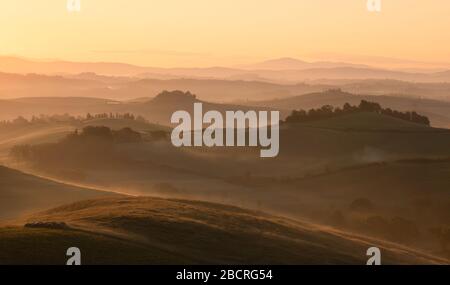 Sonnenaufgang leuchtet über einer sich abrollenden ländlichen Landschaft. Siena, Italien. Stockfoto