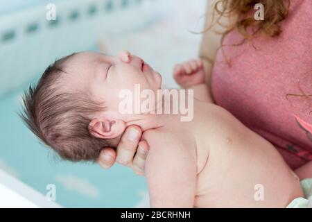 Neugeborenes kaukasisches Baby fällt in einen tiefen Schlaf an weiblichen Händen, wirft den Kopf zurück Stockfoto