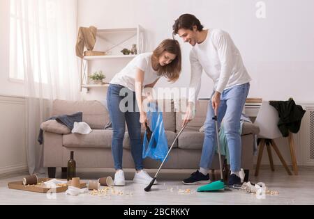 Paar Reinigung Unordentliche Zimmer Nach Party, Durchziehender Boden Und Müllabfuhr Stockfoto