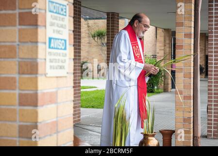 Houston, Texas, USA. April 2020. Pater TOM SMITHSON begrüßt die Gemeindemitglieder, da er an der Verteilung von Palmen in einem Drive-by-Vertrieb am Palmsonntag in der Corpus Christi Catholic Church Sunday, 5. April 2020, in Houston, Texas teilnimmt. Gutschrift: Lynn Pennington/ZUMA Wire/Alamy Live News Stockfoto