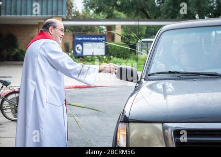 Houston, Texas, USA. April 2020. Pater TOM SMITHSON begrüßt die Gemeindemitglieder, da er an der Verteilung von Palmen in einem Drive-by-Vertrieb am Palmsonntag in der Corpus Christi Catholic Church Sunday, 5. April 2020, in Houston, Texas teilnimmt. Gutschrift: Lynn Pennington/ZUMA Wire/Alamy Live News Stockfoto