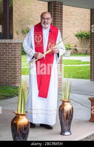 Houston, Texas, USA. April 2020. Pater TOM SMITHSON begrüßt die Gemeindemitglieder, da er an der Verteilung von Palmen in einem Drive-by-Vertrieb am Palmsonntag in der Corpus Christi Catholic Church Sunday, 5. April 2020, in Houston, Texas teilnimmt. Gutschrift: Lynn Pennington/ZUMA Wire/Alamy Live News Stockfoto