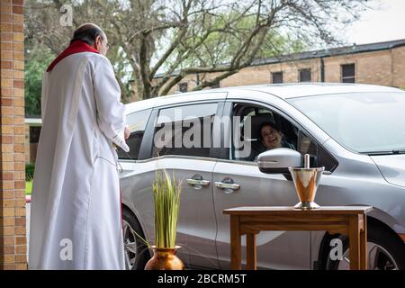 Houston, Texas, USA. April 2020. Pater TOM SMITHSON begrüßt die Gemeindemitglieder, da er an der Verteilung von Palmen in einem Drive-by-Vertrieb am Palmsonntag in der Corpus Christi Catholic Church Sunday, 5. April 2020, in Houston, Texas teilnimmt. Gutschrift: Lynn Pennington/ZUMA Wire/Alamy Live News Stockfoto