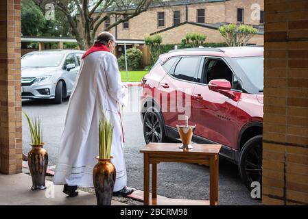 Houston, Texas, USA. April 2020. Pater TOM SMITHSON begrüßt die Gemeindemitglieder, da er an der Verteilung von Palmen in einem Drive-by-Vertrieb am Palmsonntag in der Corpus Christi Catholic Church Sunday, 5. April 2020, in Houston, Texas teilnimmt. Gutschrift: Lynn Pennington/ZUMA Wire/Alamy Live News Stockfoto