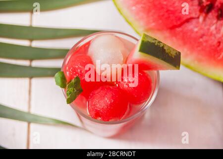 Tropischer Obstsalat mit Melone und Wassermelone Kugeln aus Glas unter dem palm leaf Stockfoto